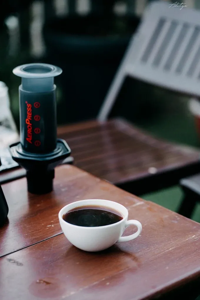 An AeroPress and a fresh cup of black coffee